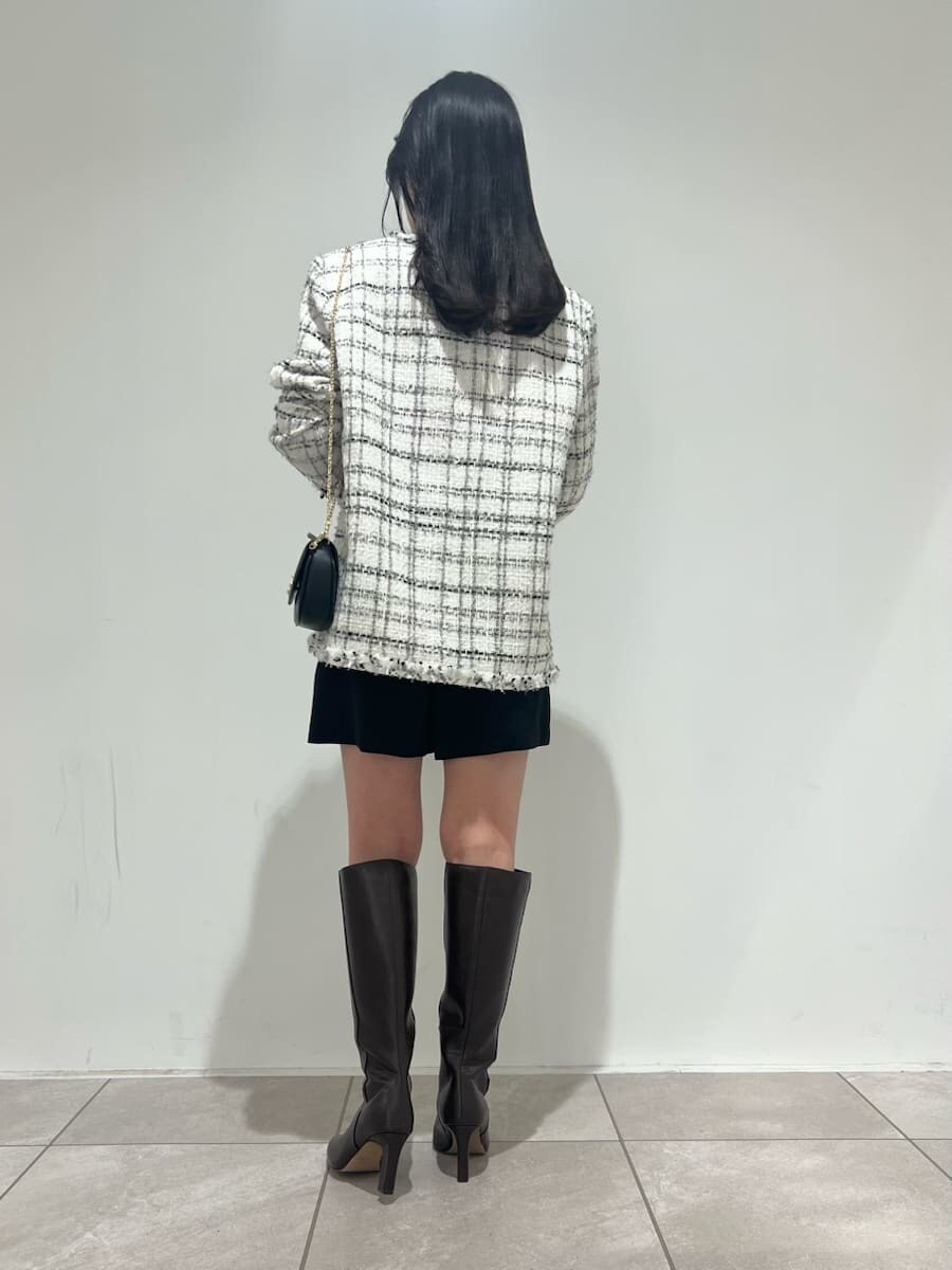 ブラウン系のブーツ、ホワイト系のノーカラージャケット、ブラック系のショルダーバッグを着用したレディースの冬コーディネートの3枚目の写真
