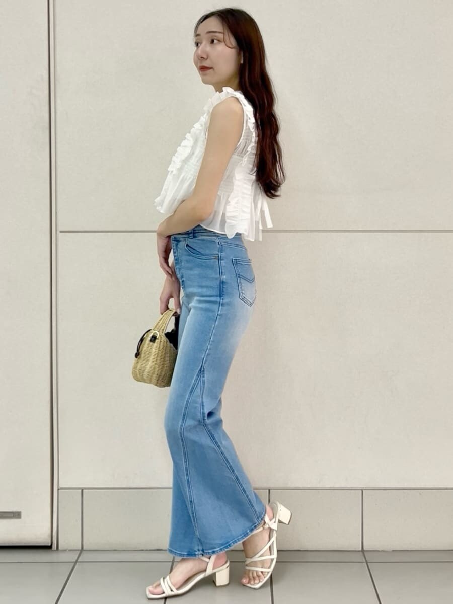 ブルー系のデニムパンツ、ブラック系のかごバッグ、ホワイト系のシャツ/ブラウスを着用したレディースの夏コーディネートの3枚目の写真