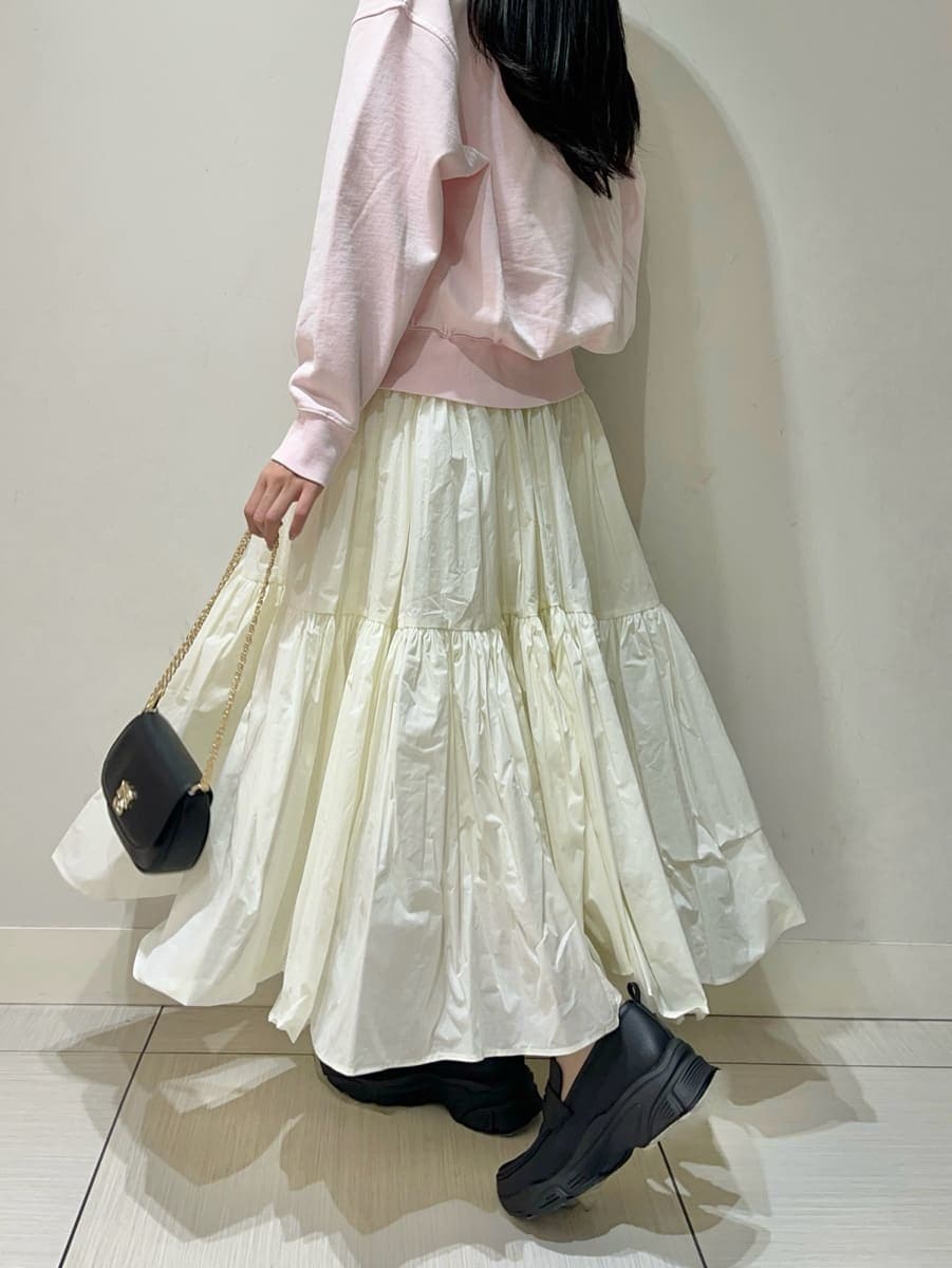 ホワイト系のスカート、ピンク系のスウェット、ブラック系のショルダーバッグを着用したレディースの春コーディネートの5枚目の写真