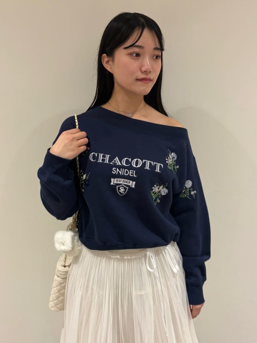 ブルー系のスウェット、ホワイト系のスカート、ブラック系のブーツを着用したレディースの秋コーディネートの4枚目の写真