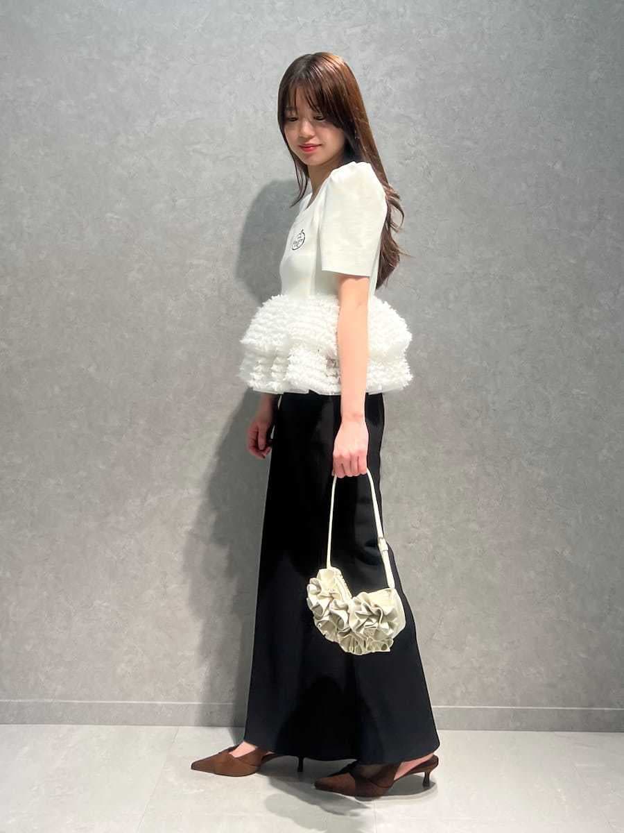 ブラック系のスカート、ホワイト系のニット/セーター、ブラウン系のパンプスを着用したレディースの春コーディネートの2枚目の写真