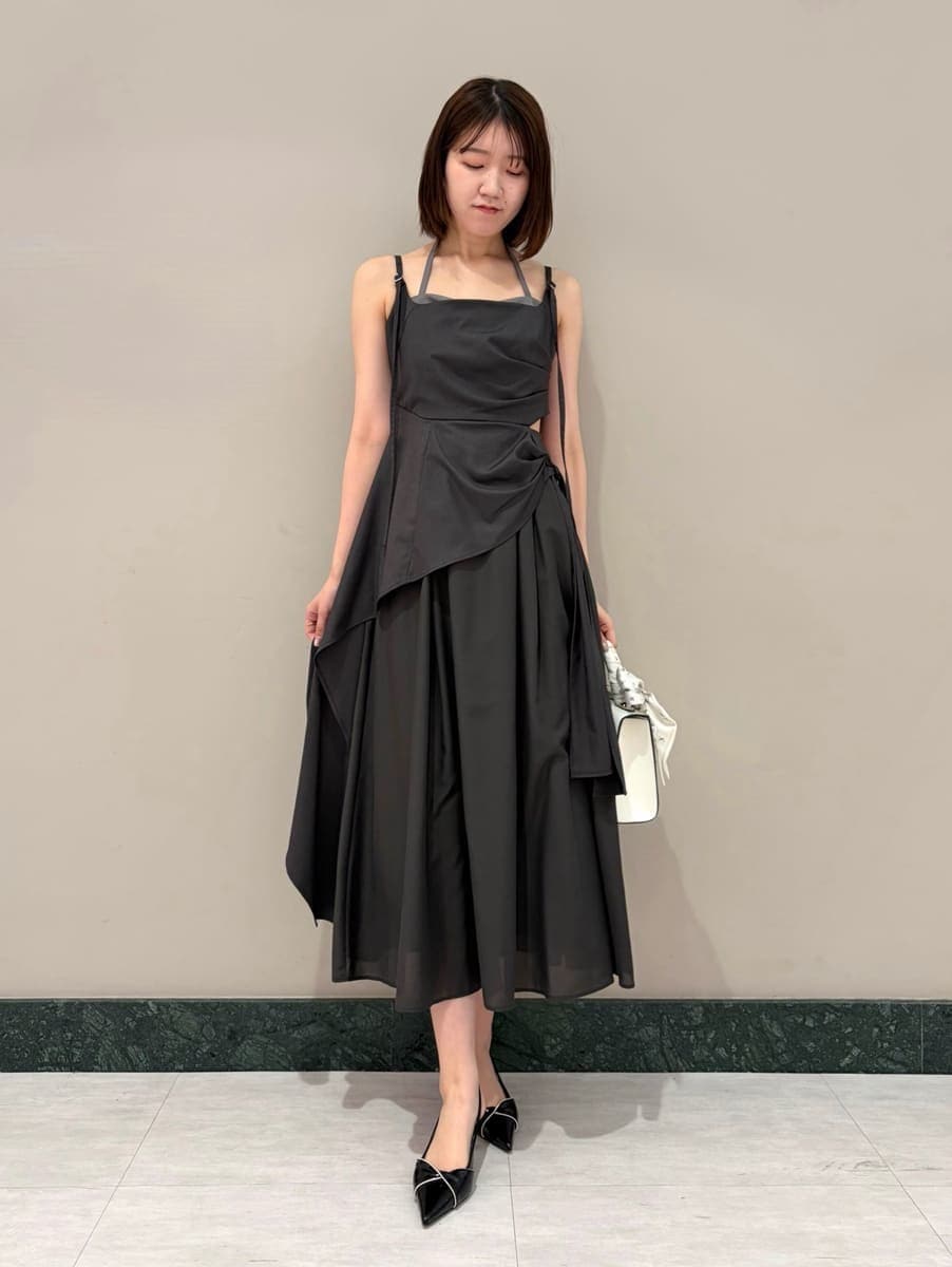 グレー系のワンピース、ホワイト系のカーディガン/ボレロ、ブラック系のパンプスを着用したレディースの春コーディネートの2枚目の写真