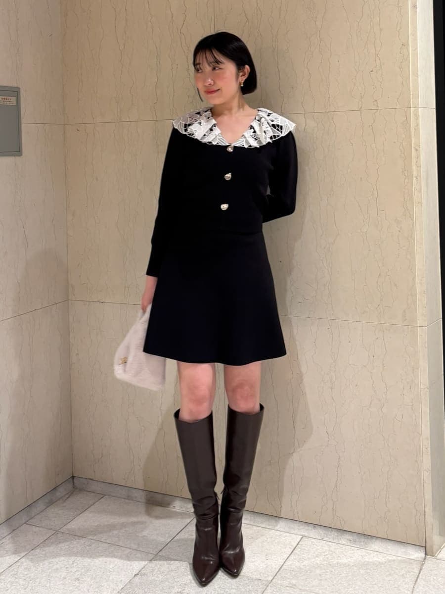 ブラウン系のブーツ、ホワイト系のハンドバッグ、ブラック系のワンピースを着用したレディースの冬コーディネートの2枚目の写真