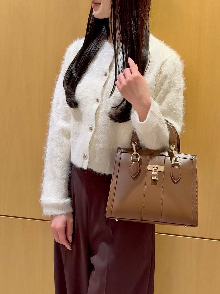 ブラウン系のスラックス、ホワイト系のカーディガン/ボレロ、ブラウン系のハンドバッグを着用したレディースの冬コーディネートの5枚目の写真