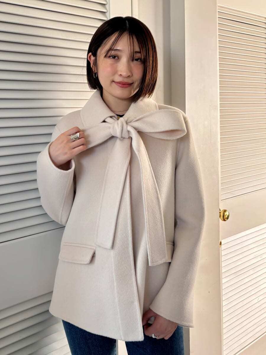 ブルー系のデニムパンツ、ブラウン系のハンドバッグを着用したレディースの秋コーディネートの2枚目の写真