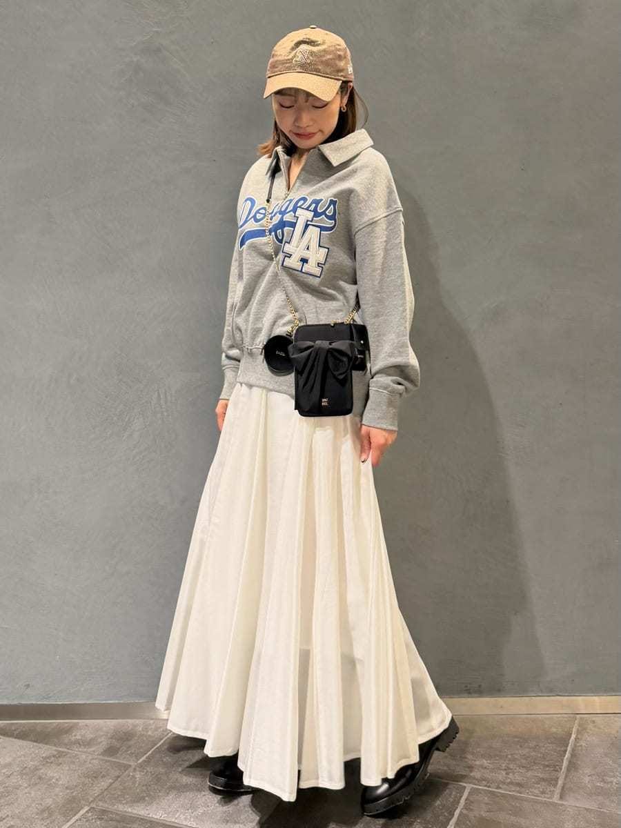 グレー系のスウェット、ブラック系のショルダーバッグ、ホワイト系のスカートを着用したレディースの春コーディネートの2枚目の写真