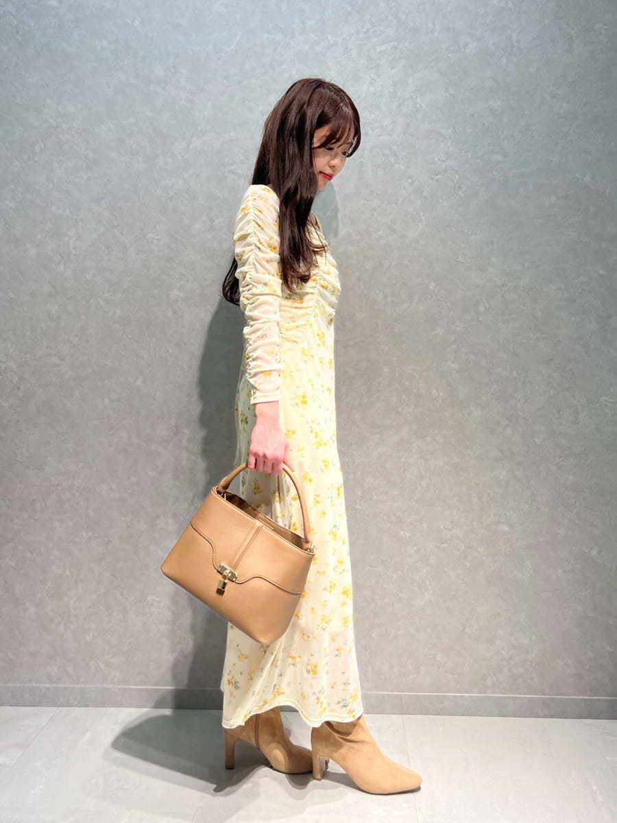 ベージュ系のブーツ、イエロー系のワンピース、イエロー系のハンドバッグを着用したレディースの冬コーディネートの3枚目の写真
