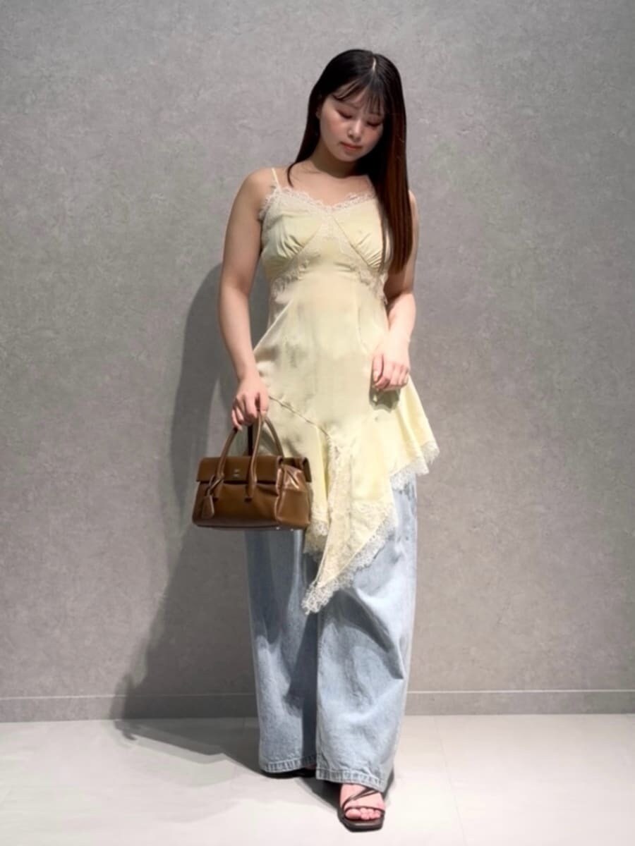 ブルー系のデニムパンツ、ブラウン系のボストンバッグ、イエロー系のキャミソールを着用したレディースの夏コーディネートの2枚目の写真