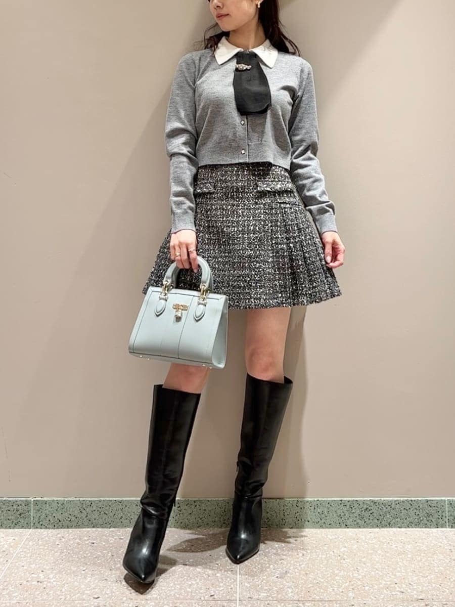 ブラック系のブーツ、グレー系のスカート、ブルー系のハンドバッグを着用したレディースの冬コーディネートの2枚目の写真