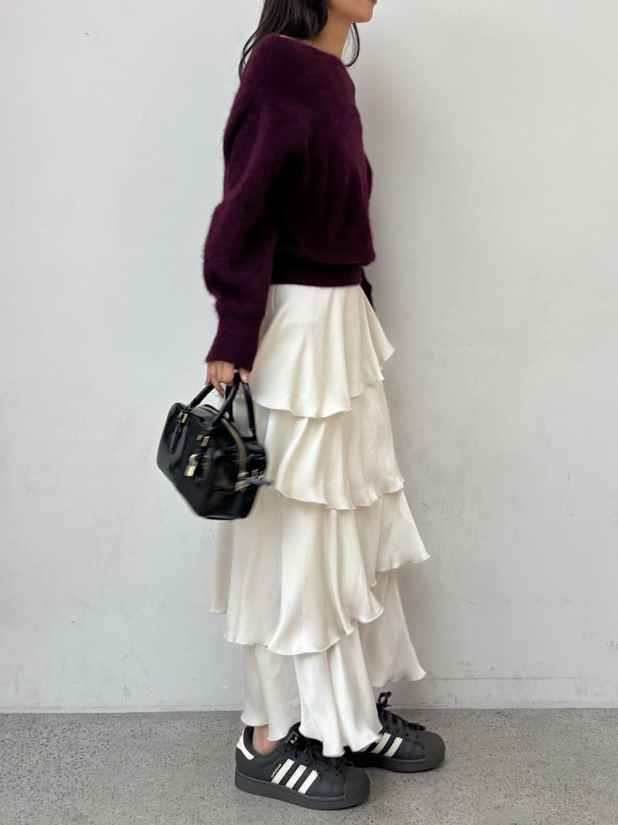 レッド系のニット/セーター、ホワイト系のスカート、グレー系のスニーカーを着用したレディースの秋コーディネートの2枚目の写真