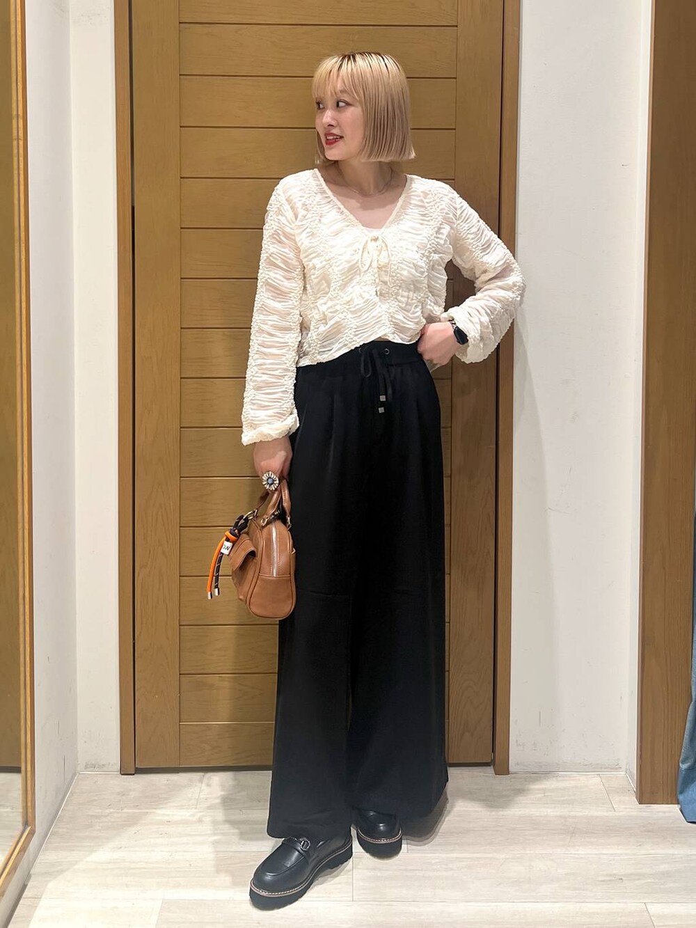 ブラック系のその他パンツ、ブラウン系のボストンバッグ、ブラック系のローファーを着用したレディースの秋コーディネートの2枚目の写真