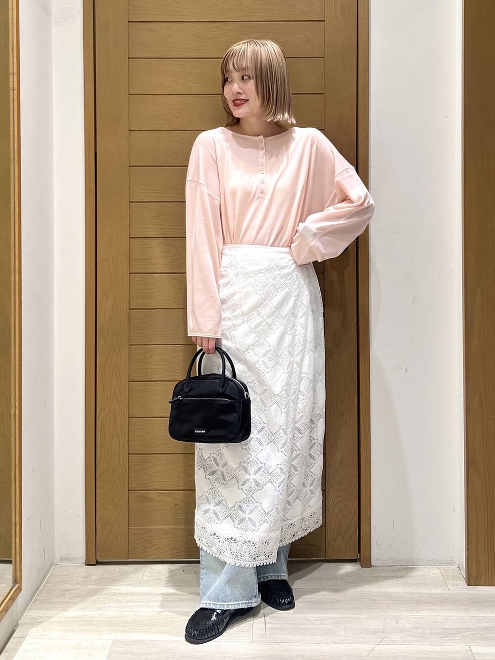 ブルー系のデニムパンツ、ブラック系のハンドバッグ、ブラック系のローファーを着用したレディースの春コーディネートの2枚目の写真