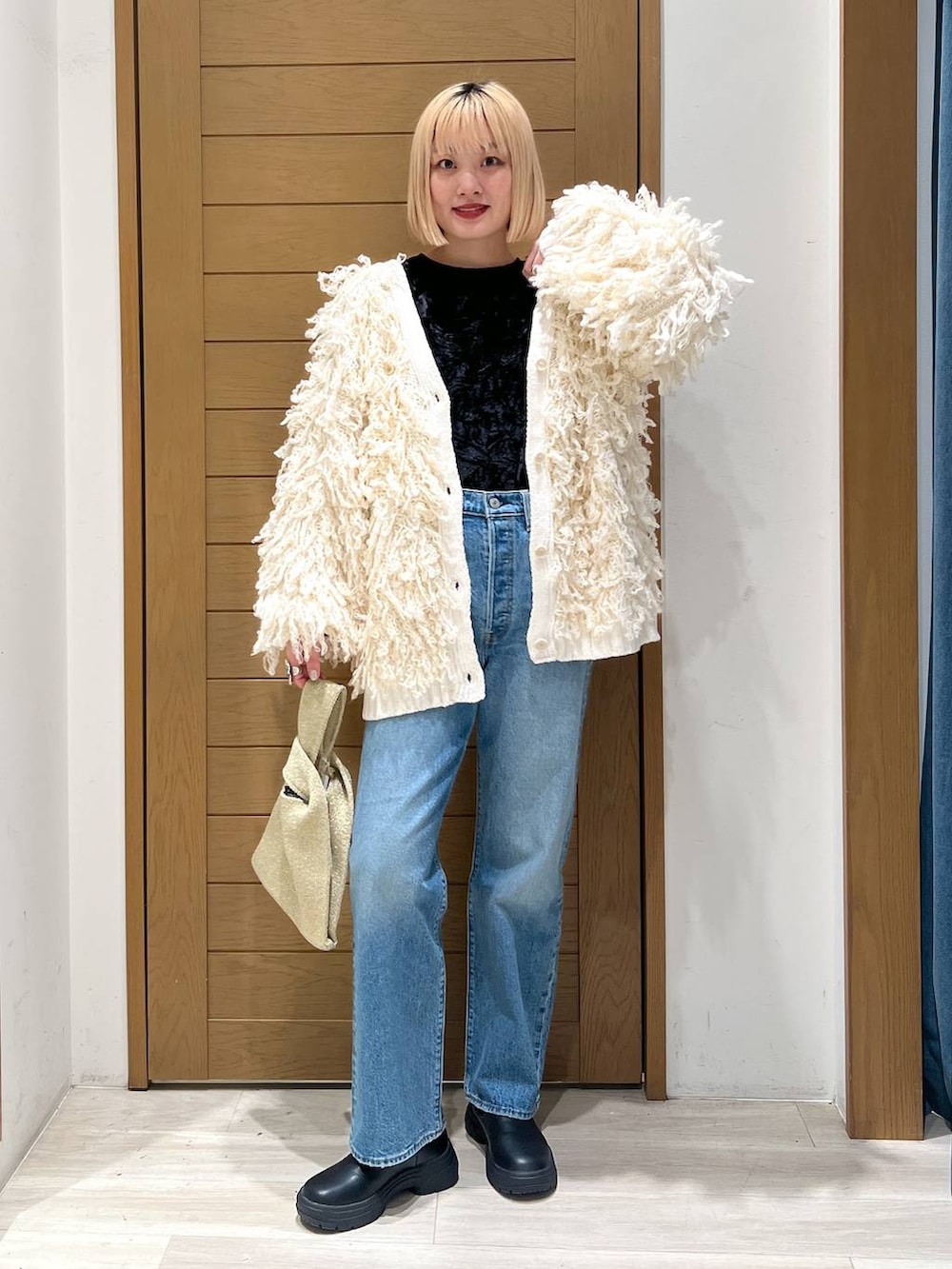 ブルー系のデニムパンツ、ホワイト系のカーディガン/ボレロ、イエロー系のハンドバッグを着用したレディースの冬コーディネートの5枚目の写真