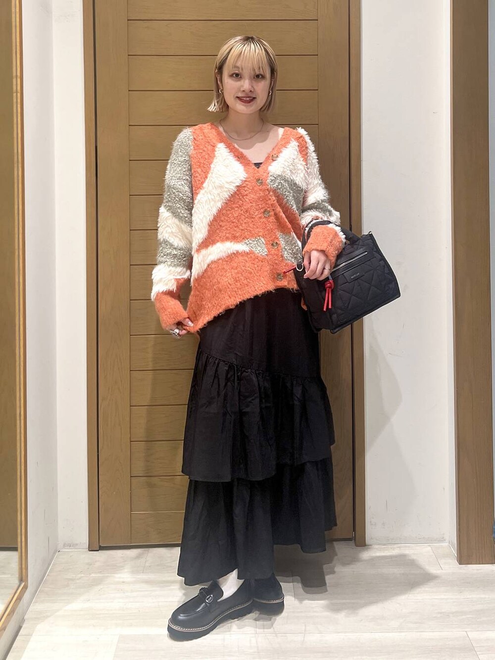 ブラック系のショルダーバッグ、ブラック系のローファー、ブラック系のスカートを着用したレディースの秋コーディネートの6枚目の写真