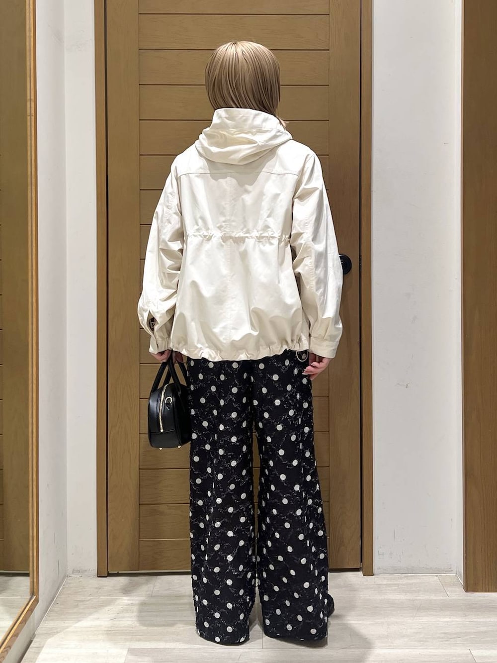 ホワイト系のマウンテンパーカー、ブラック系のローファー、ブラック系のハンドバッグを着用したレディースの春コーディネートの5枚目の写真