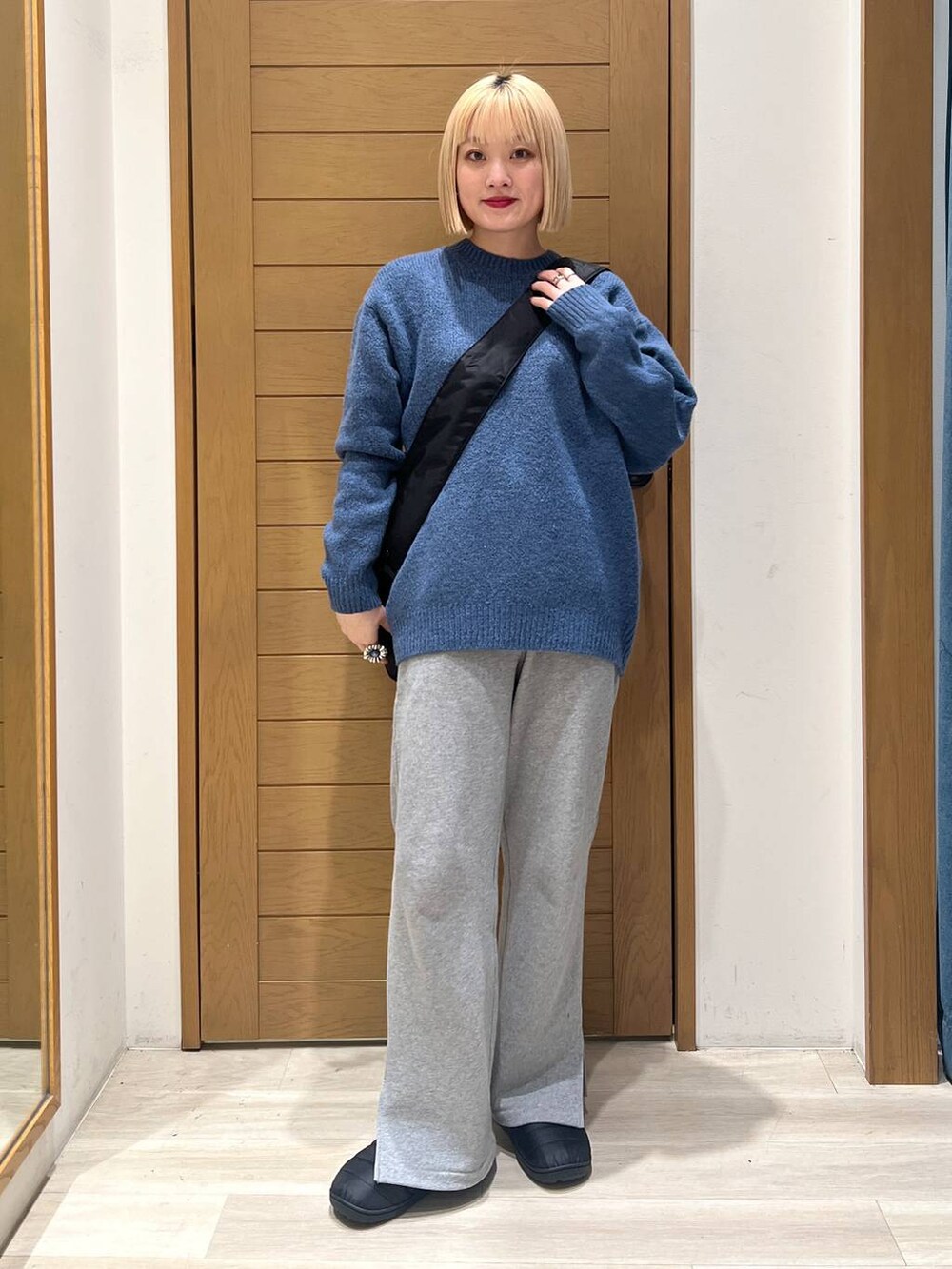 グレー系のスウェットパンツ、ブルー系のニット/セーター、ブラック系のショルダーバッグを着用したレディースの冬コーディネートの4枚目の写真