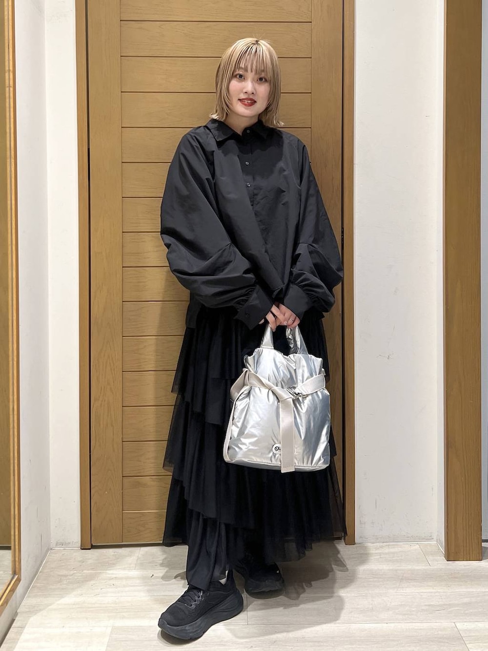 シルバー系のトートバッグ、ブラック系のシャツ/ブラウス、ブラック系のスカートを着用したレディースの春コーディネートの3枚目の写真