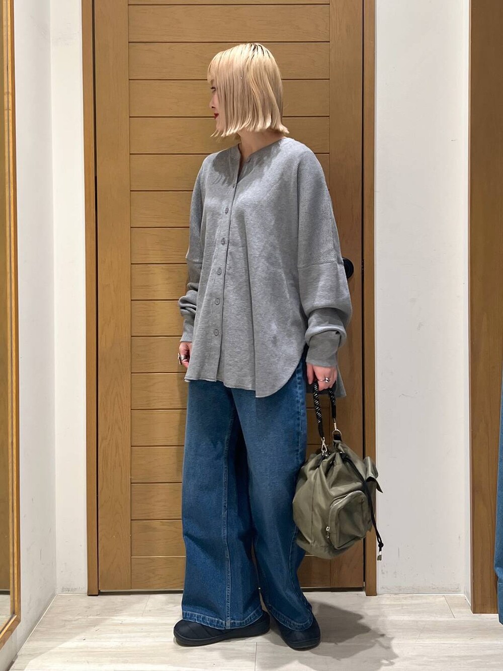 グリーン系のショルダーバッグ、グレー系のカーディガン/ボレロ、ブルー系のデニムパンツを着用したレディースの冬コーディネートの3枚目の写真