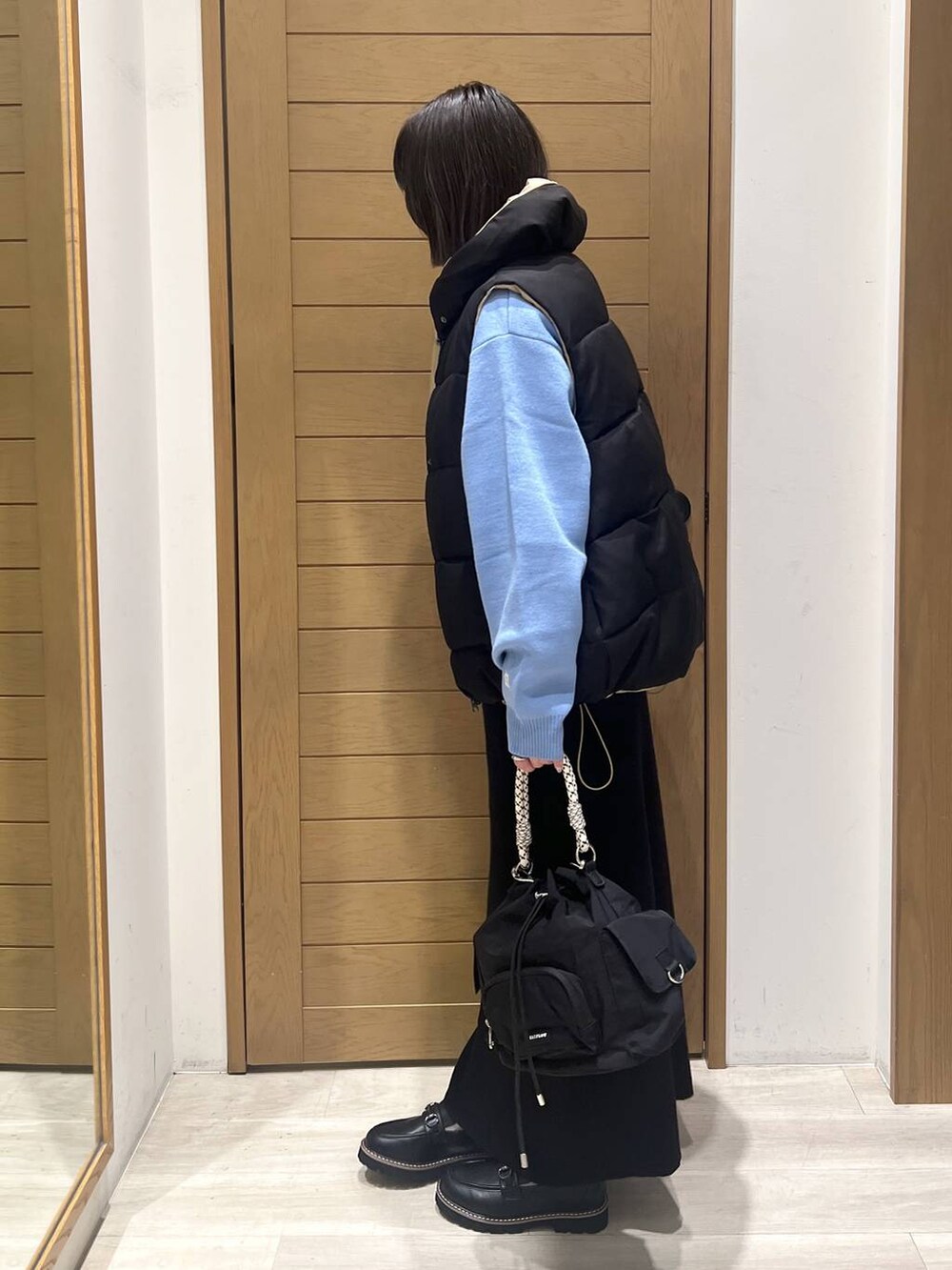 ブルー系のニット/セーター、ブラック系のローファー、ブラック系のハンドバッグを着用したレディースの秋コーディネートの4枚目の写真