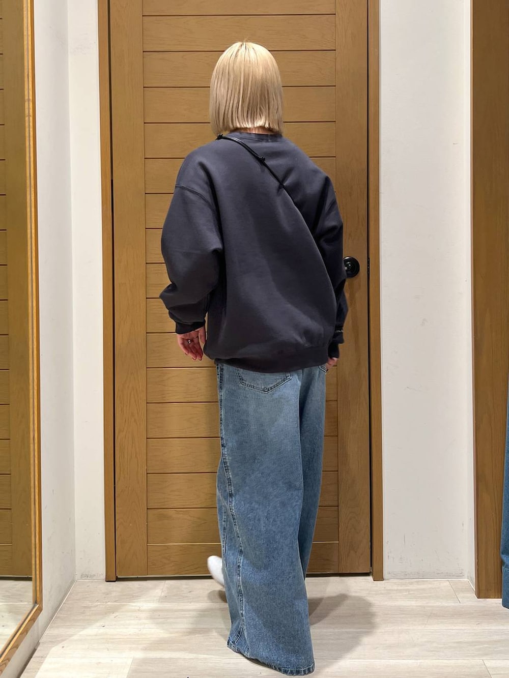 グレー系のショルダーバッグ、ブルー系のデニムパンツ、グレー系のスウェットを着用したレディースの冬コーディネートの3枚目の写真