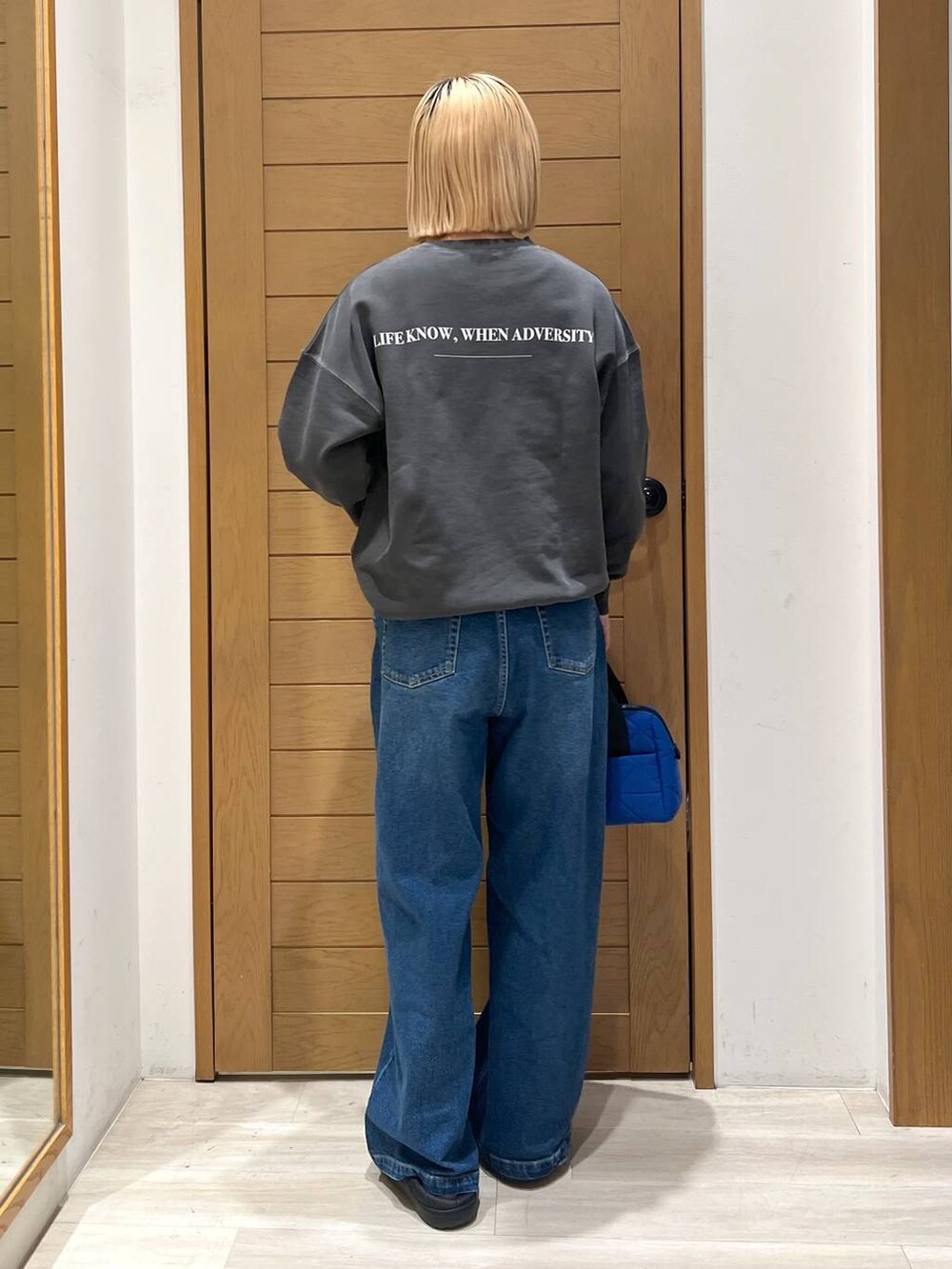 グレー系のスウェット、ブルー系のハンドバッグ、ブルー系のデニムパンツを着用したレディースの冬コーディネートの3枚目の写真