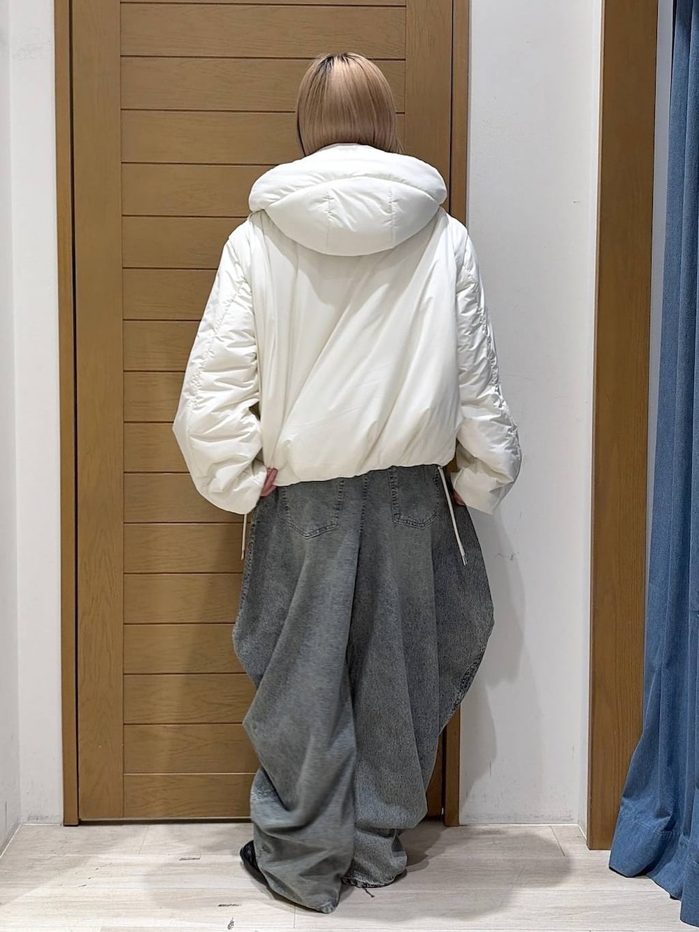 ブラック系のスリッポン、ブルー系のデニムパンツ、ホワイト系のブルゾンを着用したレディースの秋コーディネートの5枚目の写真