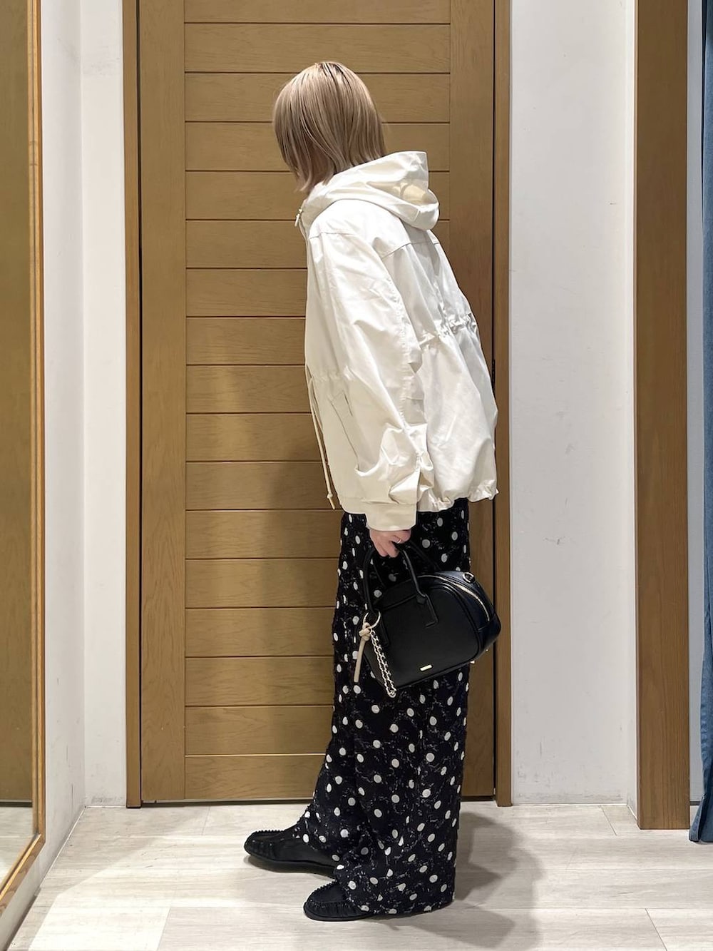 ホワイト系のマウンテンパーカー、ブラック系のローファー、ブラック系のハンドバッグを着用したレディースの春コーディネートの4枚目の写真