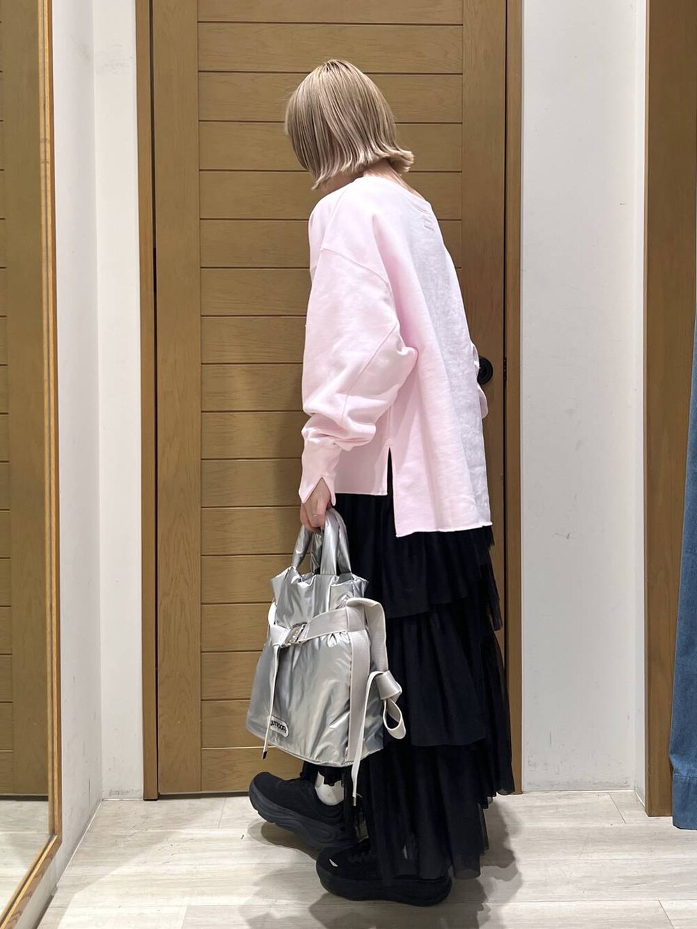 シルバー系のトートバッグ、ピンク系のスウェット、ブラック系のスカートを着用したレディースの春コーディネートの6枚目の写真