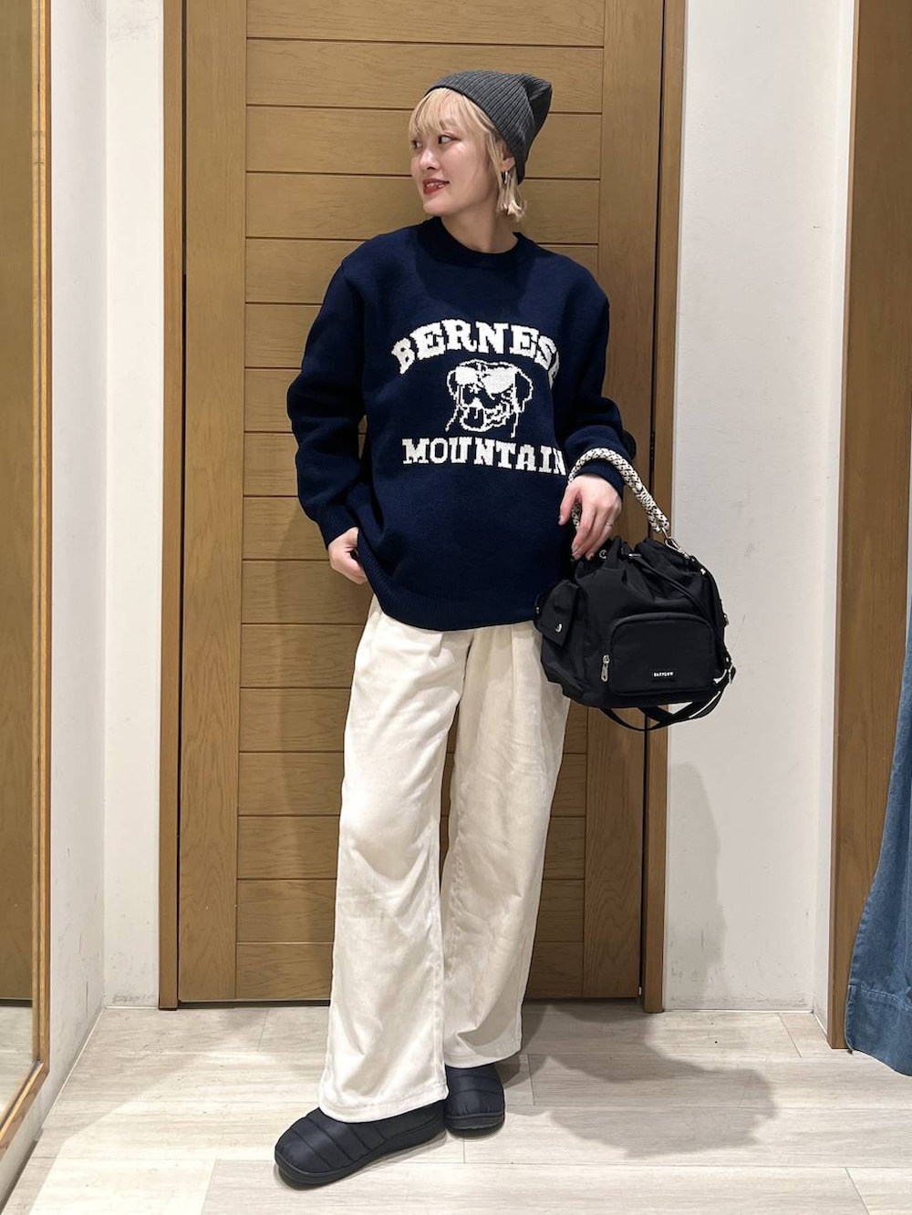 ブラック系のハンドバッグ、ホワイト系のその他パンツ、ブルー系のニット/セーターを着用したレディースの冬コーディネートの2枚目の写真