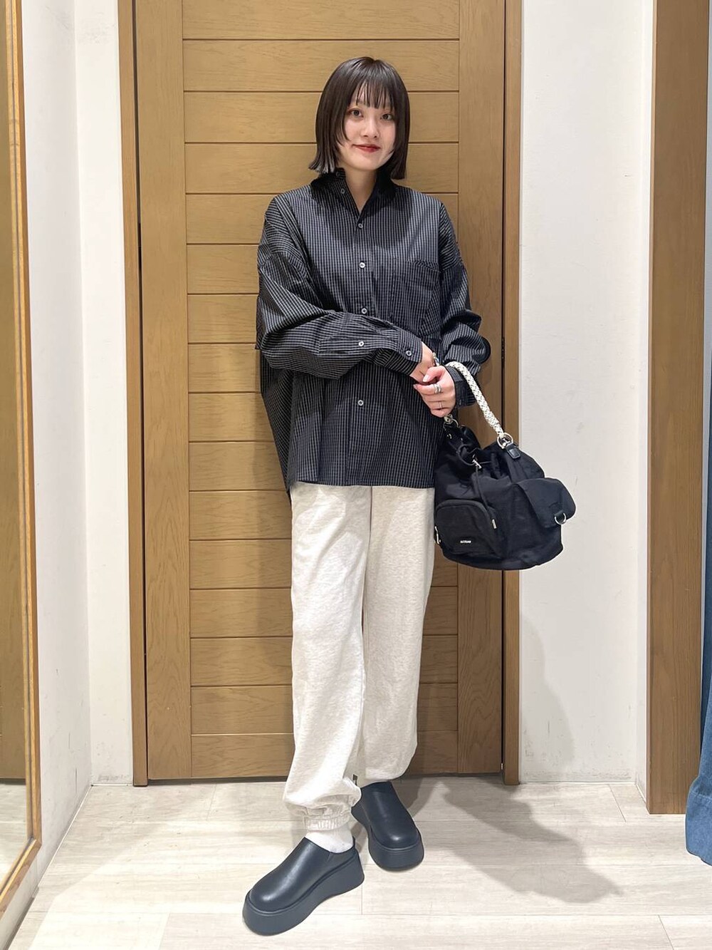 ベージュ系のスウェットパンツ、ブラック系のサンダル、ブラック系のハンドバッグを着用したレディースの秋コーディネートの5枚目の写真