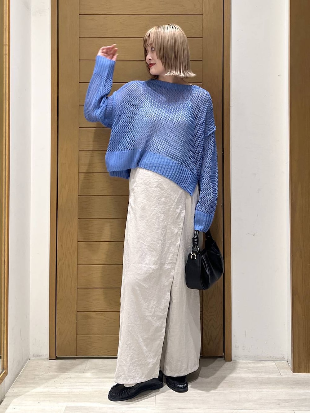 ブラック系のハンドバッグ、ブラック系のローファー、ブルー系のニット/セーターを着用したレディースの春コーディネートの2枚目の写真