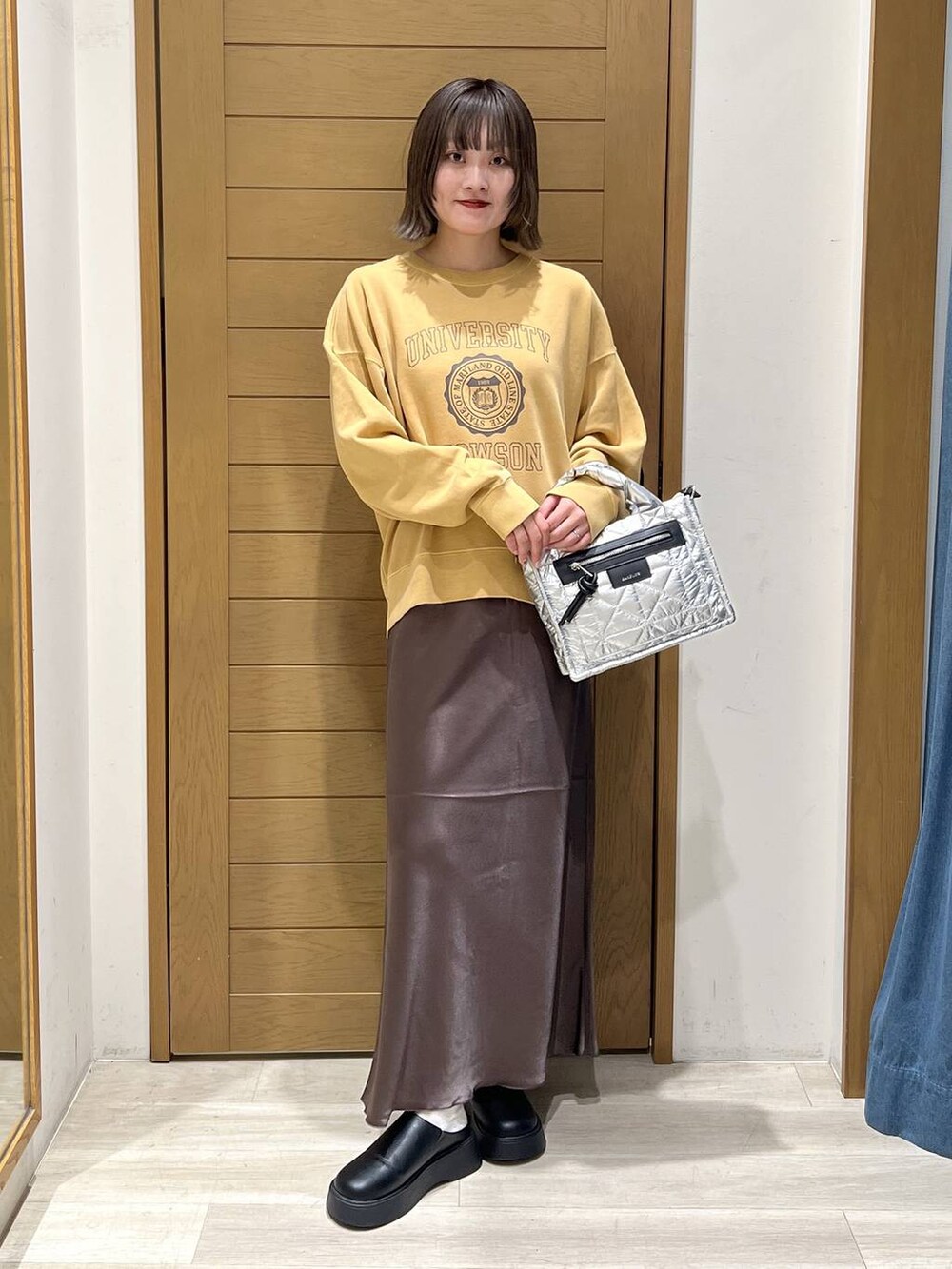 シルバー系のショルダーバッグ、ブラック系のサンダル、イエロー系のスウェットを着用したレディースの秋コーディネートの5枚目の写真