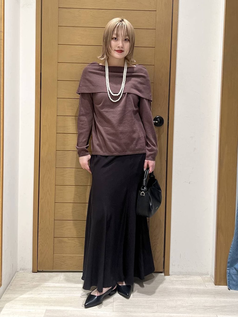 ブラック系のハンドバッグ、ブラック系のパンプス、ブラウン系のニット/セーターを着用したレディースの春コーディネートの6枚目の写真