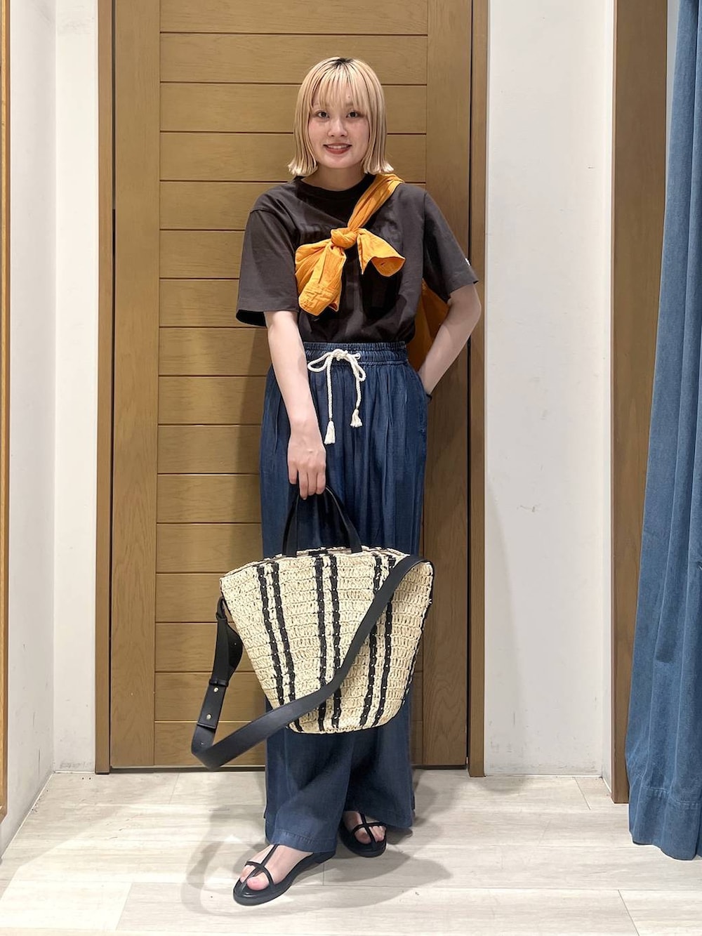ブラック系のTシャツ/カットソー、オレンジ系のシャツ/ブラウス、ブルー系のデニムパンツを着用したレディースの春コーディネートの2枚目の写真