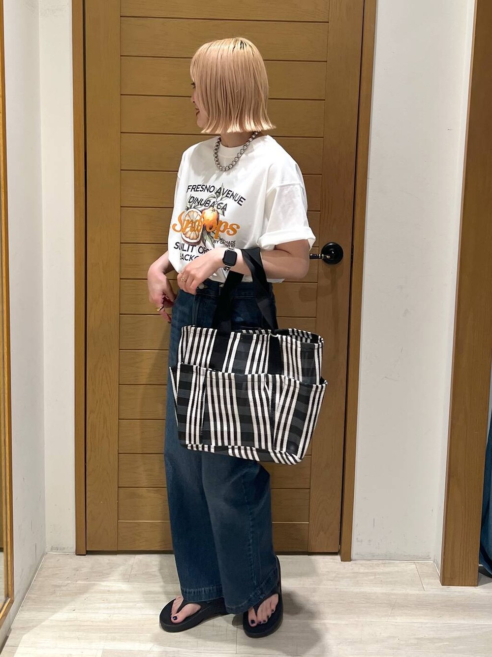 ブルー系のデニムパンツ、オレンジ系のTシャツ/カットソー、ブラック系のサンダルを着用したレディースの夏コーディネートの4枚目の写真