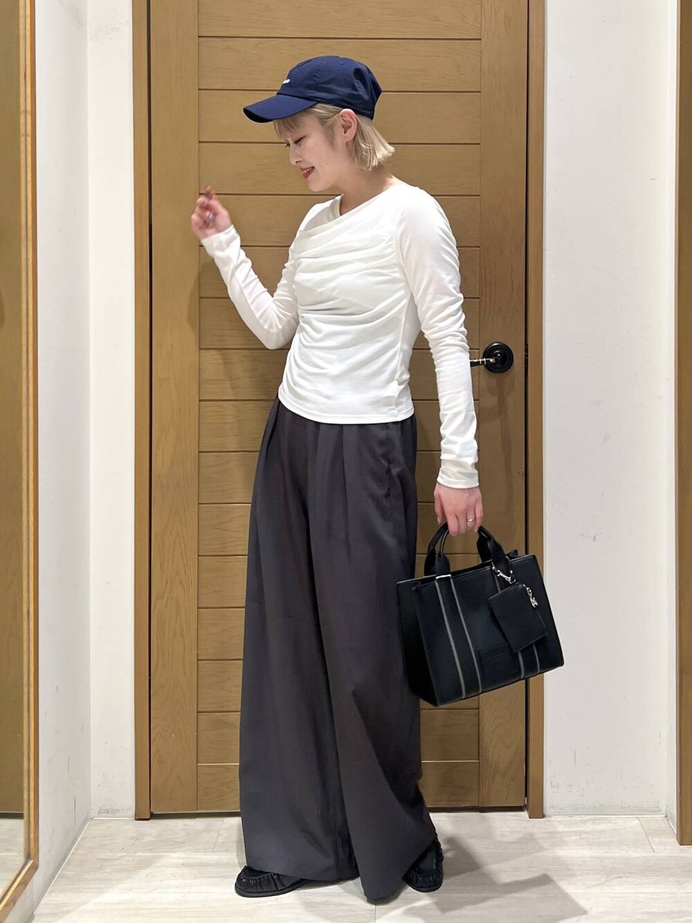 ブラック系のハンドバッグ、ブラック系のローファー、グレー系のその他パンツを着用したレディースの冬コーディネートの5枚目の写真