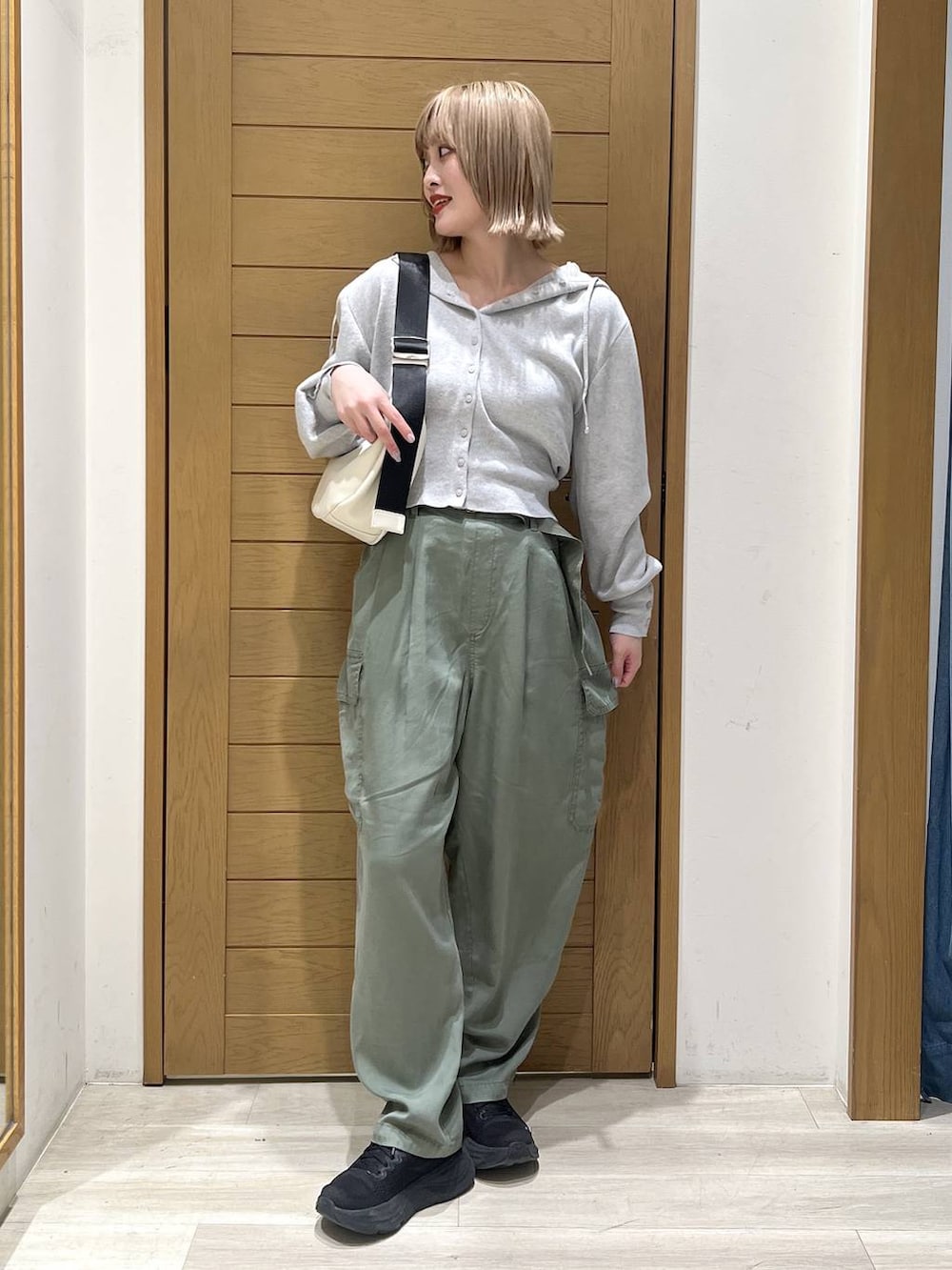グリーン系のカーゴパンツ、ホワイト系のショルダーバッグ、グレー系のパーカーを着用したレディースの春コーディネートの2枚目の写真