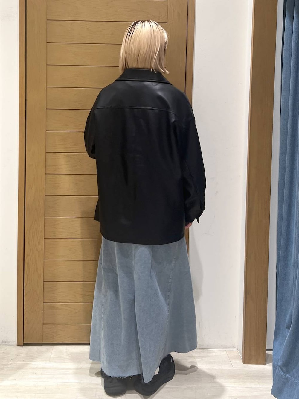 ブラック系のハンドバッグ、ブラック系のブルゾン、ブルー系のスカートを着用したレディースの秋コーディネートの4枚目の写真