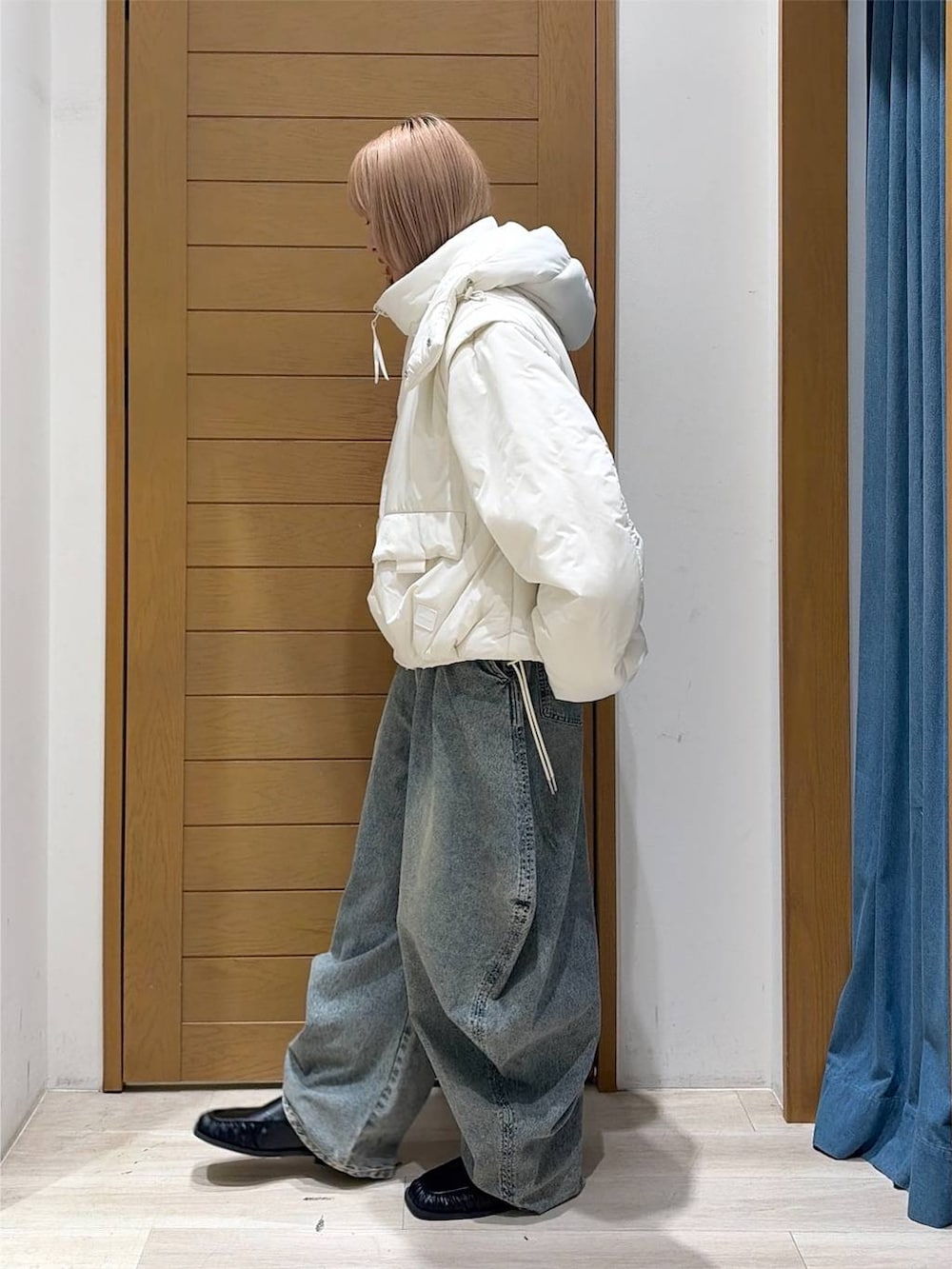 ブラック系のスリッポン、ブルー系のデニムパンツ、ホワイト系のブルゾンを着用したレディースの秋コーディネートの4枚目の写真
