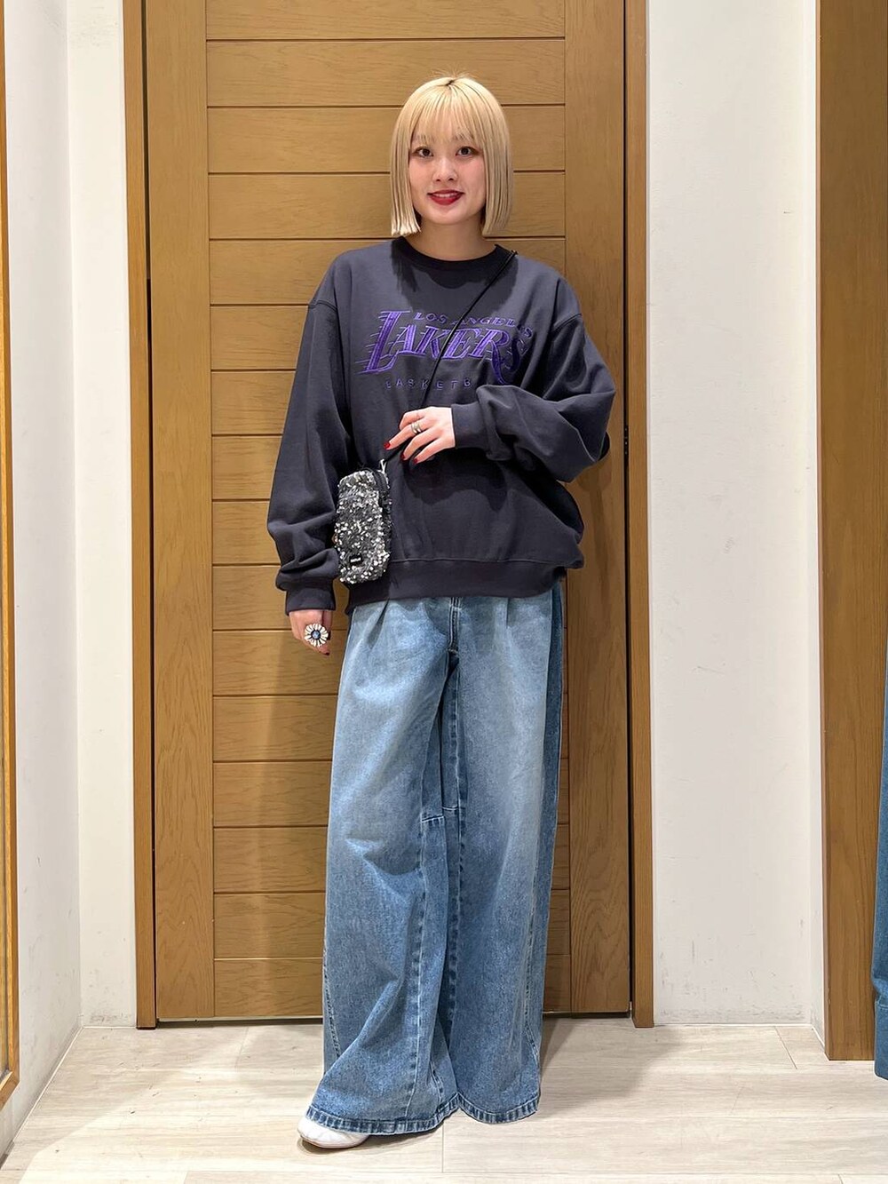 グレー系のショルダーバッグ、ブルー系のデニムパンツ、グレー系のスウェットを着用したレディースの冬コーディネートの5枚目の写真