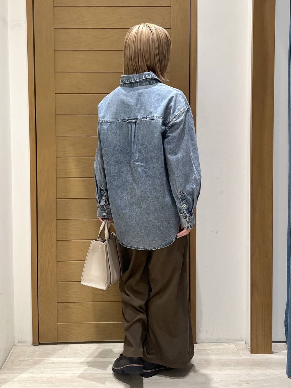 ブラック系のローファー、ベージュ系のハンドバッグ、ブルー系のシャツ/ブラウスを着用したレディースの春コーディネートの4枚目の写真