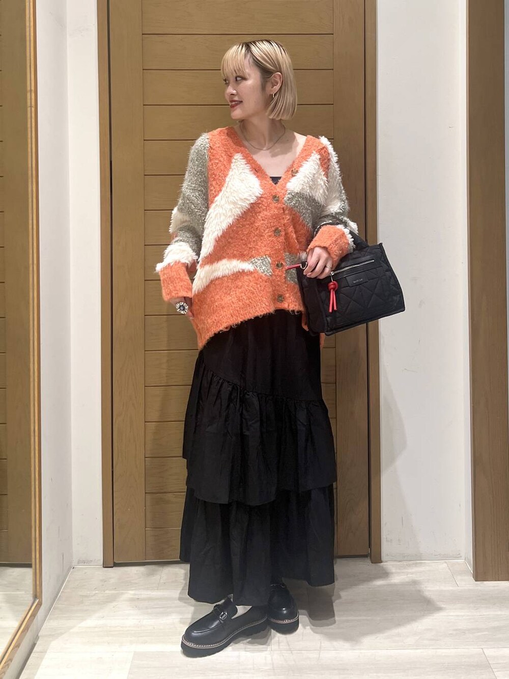 ブラック系のショルダーバッグ、ブラック系のローファー、ブラック系のスカートを着用したレディースの秋コーディネートの2枚目の写真