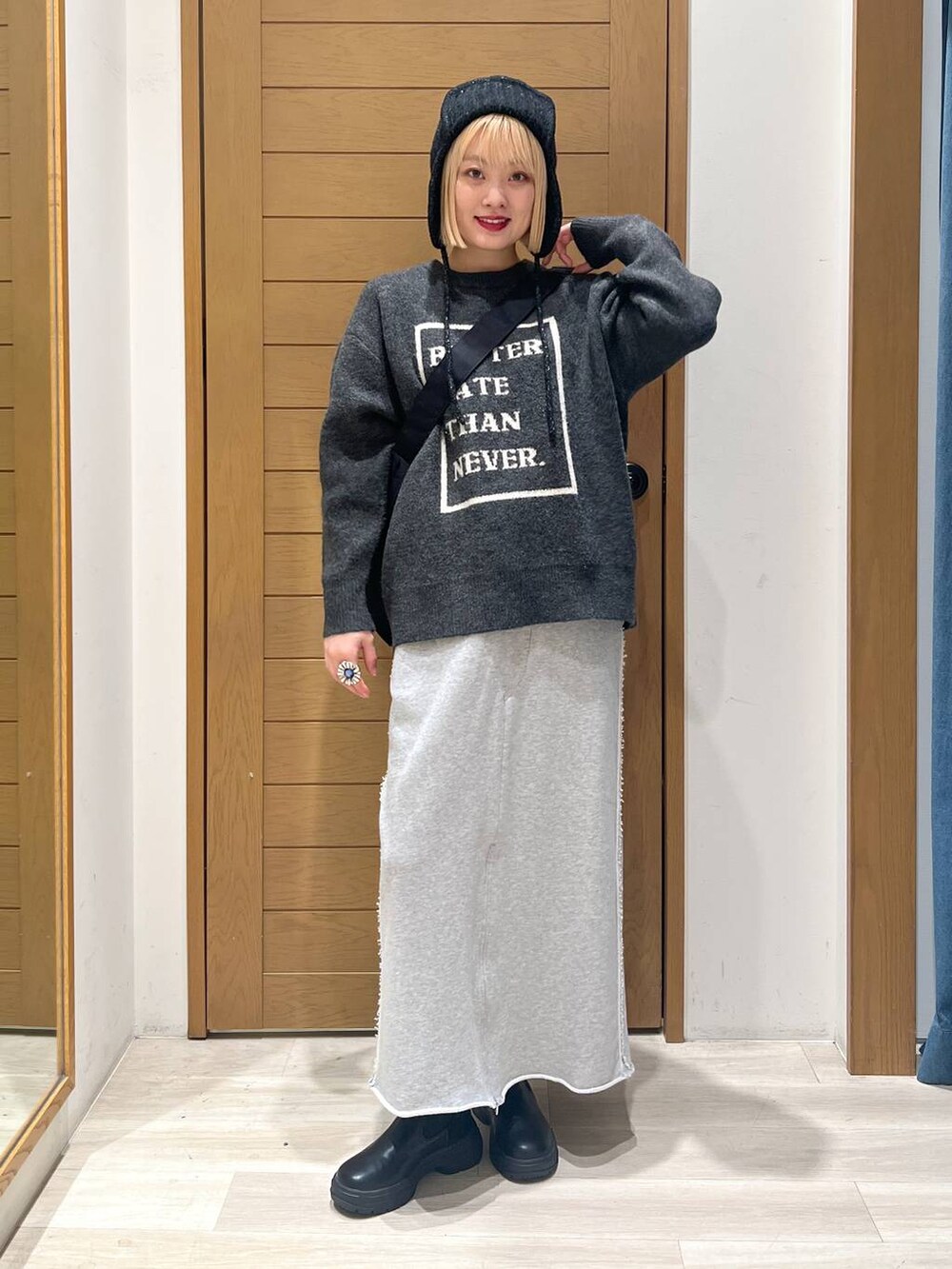 ブラック系のブーツ、グレー系のニット/セーター、ブラック系のショルダーバッグを着用したレディースの冬コーディネートの2枚目の写真