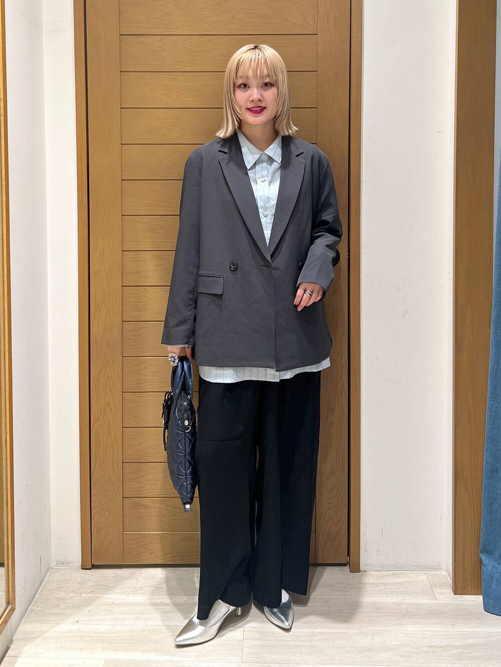 シルバー系のパンプス、ブラック系のその他パンツ、ブルー系のハンドバッグを着用したレディースの春コーディネートの4枚目の写真