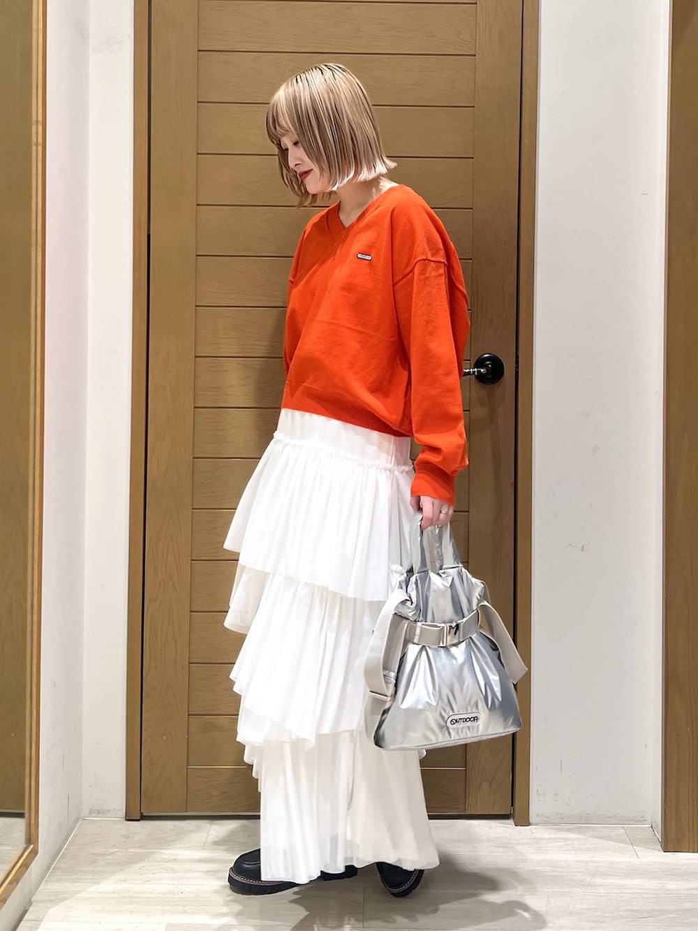 シルバー系のトートバッグ、ブラック系のローファー、オレンジ系のニット/セーターを着用したレディースの春コーディネートの3枚目の写真
