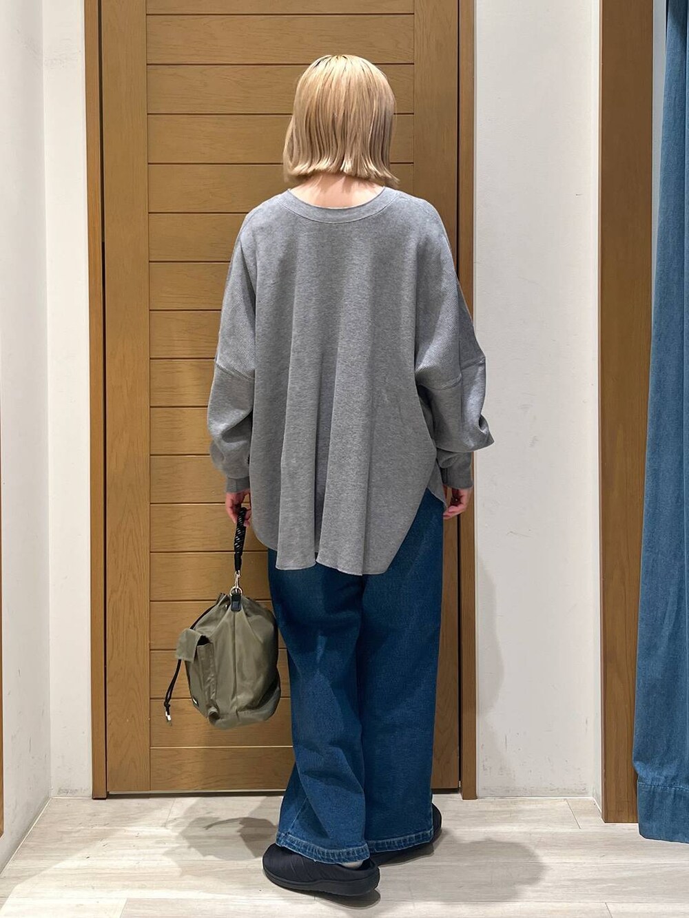 グリーン系のショルダーバッグ、グレー系のカーディガン/ボレロ、ブルー系のデニムパンツを着用したレディースの冬コーディネートの4枚目の写真