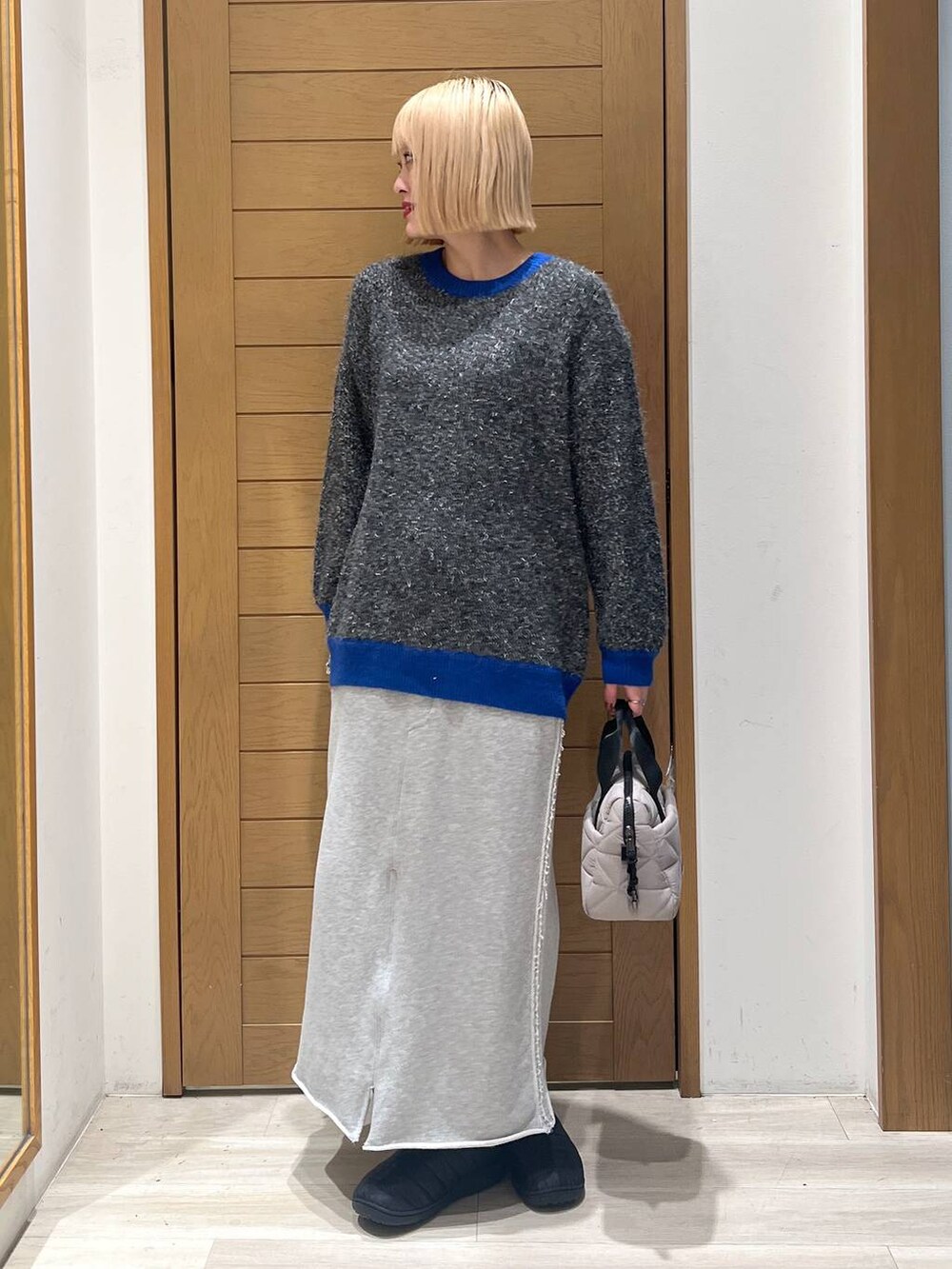 グレー系のニット/セーター、ベージュ系のハンドバッグ、グレー系のスカートを着用したレディースの冬コーディネートの3枚目の写真