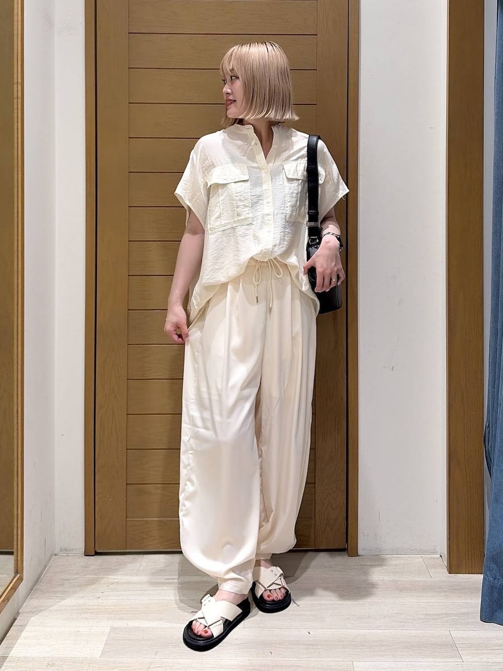 ベージュ系のその他パンツ、ホワイト系のシャツ/ブラウス、ホワイト系のサンダルを着用したレディースの夏コーディネートの2枚目の写真
