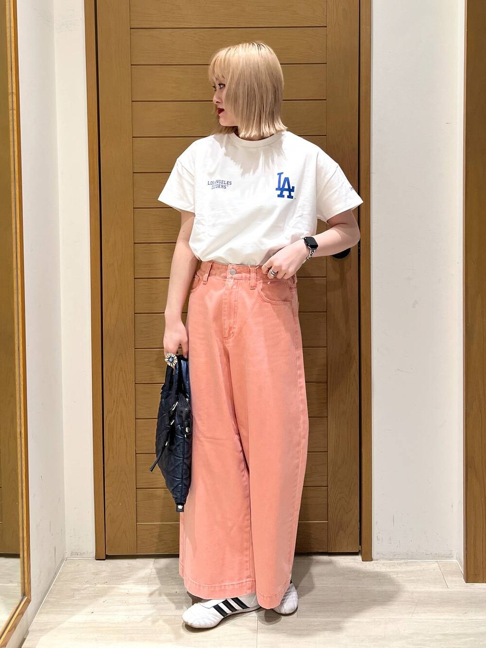 ピンク系のデニムパンツ、ブルー系のハンドバッグ、ホワイト系のTシャツ/カットソーを着用したレディースの春コーディネートの6枚目の写真