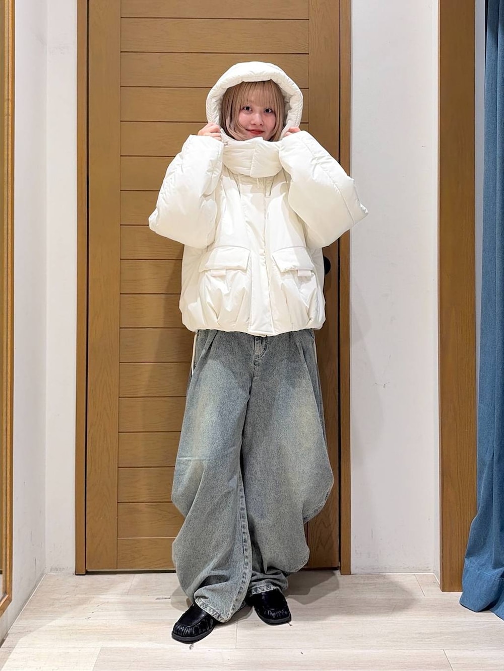 ブラック系のスリッポン、ブルー系のデニムパンツ、ホワイト系のブルゾンを着用したレディースの秋コーディネートの2枚目の写真